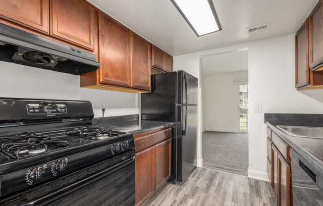 A kitchen with a black stove top oven and black refrigerator with wooden cabinets.