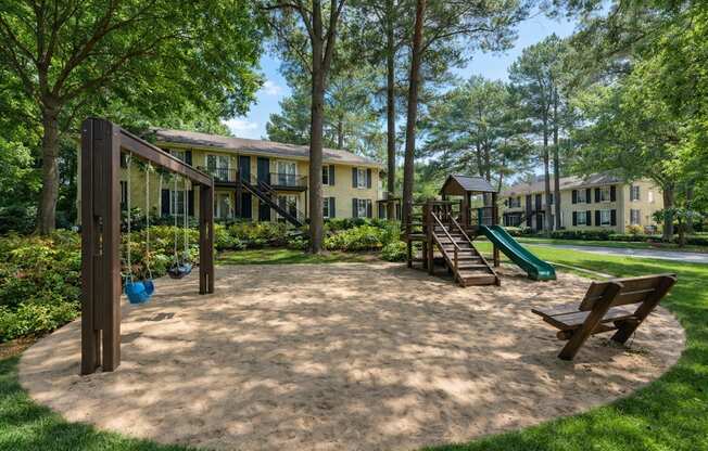 A playground with a slide, swings and a sandbox.