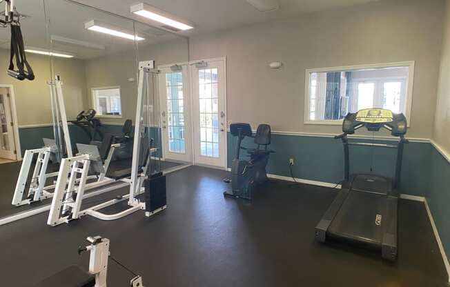 Fitness center with exercise bike, treadmill, elliptical, weight machines, and wall made up mirrors
