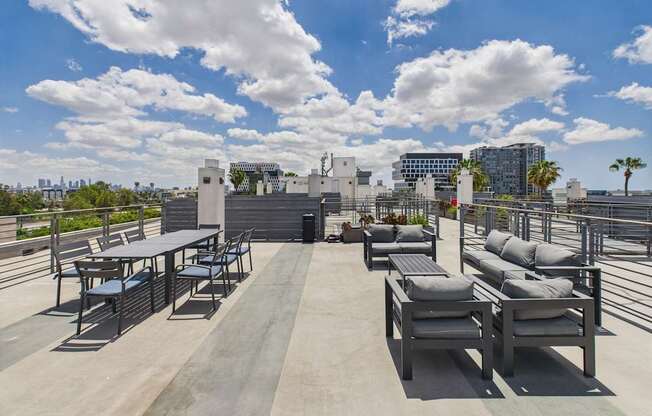 A rooftop patio with a table and chairs overlooking a city skyline.