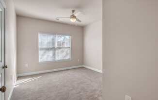 an empty living room with a ceiling fan and a window