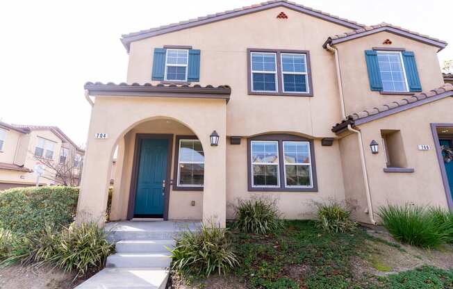 the front of a two story apartment with a blue door at The Vines at Riverpark, LLC, California, 93036