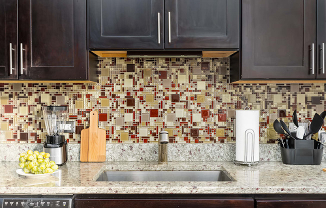 a kitchen counter with a sink and a tile backsplash