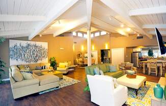A living room with a white couch and a painting on the wall.