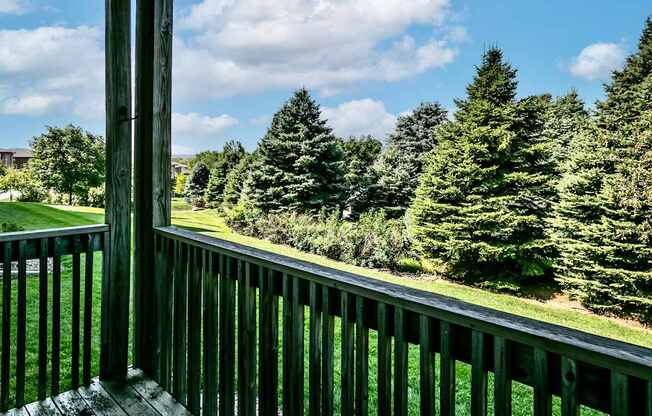 the view from the deck of a house overlooking a lawn and trees