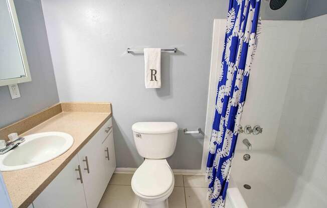 A white toilet sits in a bathroom next to a sink and a shower.