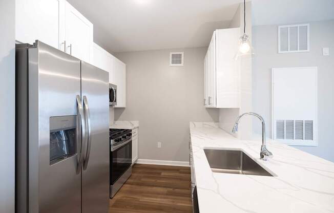 A modern kitchen with a stainless steel refrigerator and a marble countertop. at Harbor Pointe, Bayonne