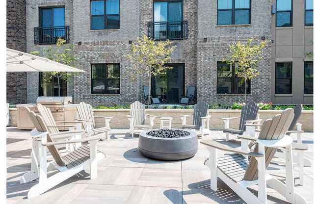 A patio with white chairs and a fire pit.