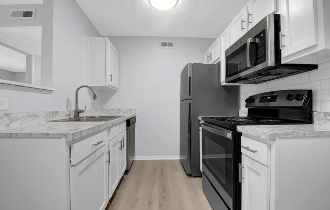 a kitchen with white cabinets and black appliances