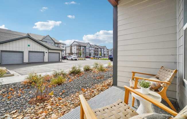 the front porch of a house with a chair and a gravel yard