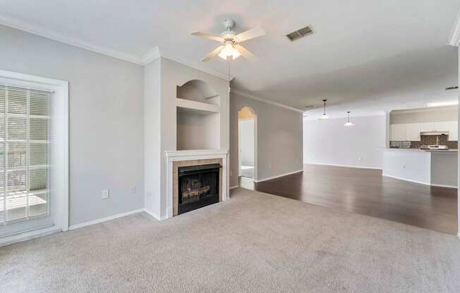A living room with a fireplace and a ceiling fan.