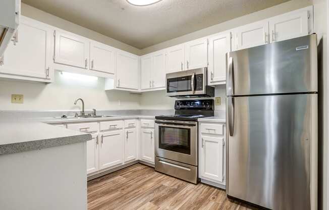 kitchen with white cabinetry, stainless appliances, and hardwood-style flooring