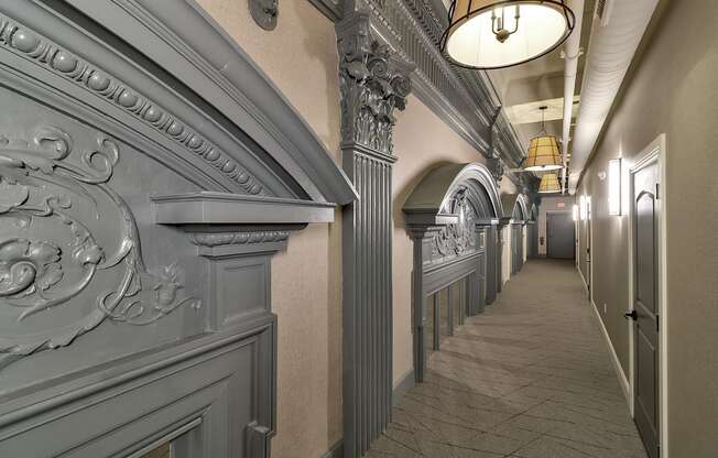 a long hallway with a long row of columns and a ceiling light at The Knights @ 506 Delaware Apartments, Buffalo, NY