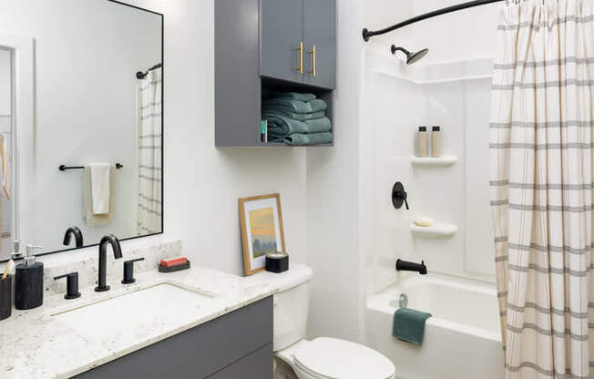 A bathroom with a white toilet, sink, and a shower with a white curtain.