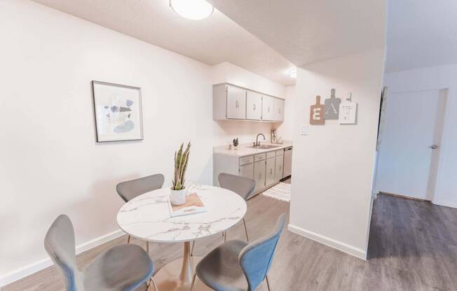 a dining area with a table and chairs and a kitchen in the background