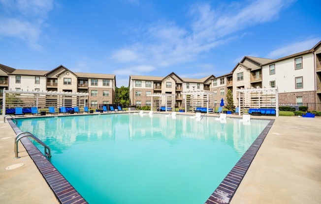 A large swimming pool in front of apartment buildings.