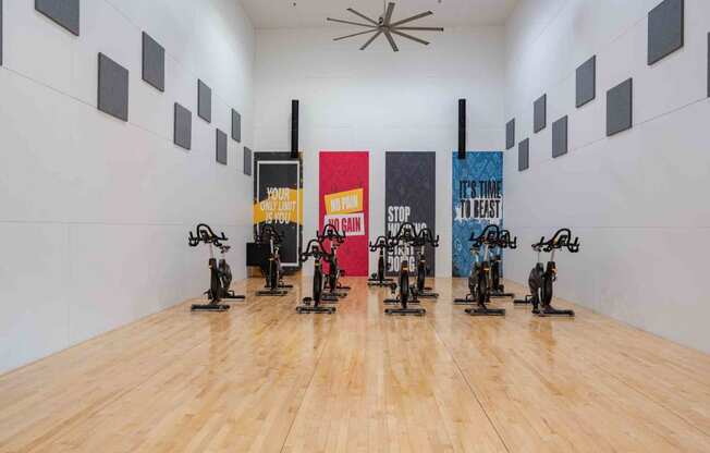 a gym with a wooden floor and a white wall with colourful paintings on it