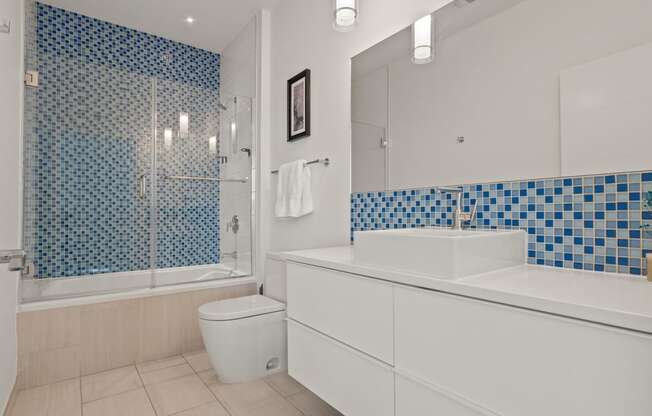 a bathroom with white cabinets and blue and white tile