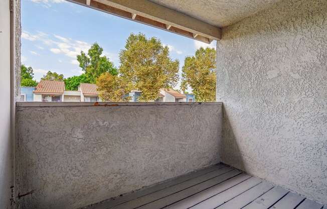 a balcony with a wooden floor and a view of the trees