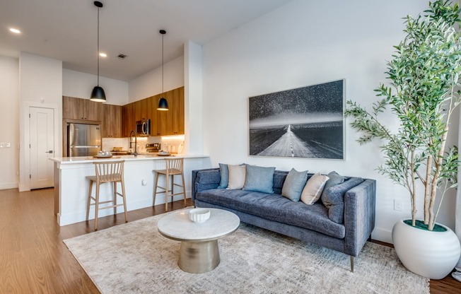 A modern living room with a grey sofa, a coffee table, and a large painting on the wall.