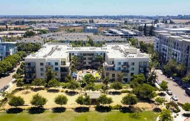 an aerial view of an apartment complex with trees and grass in the foreground and buildings in the