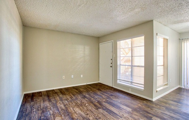 an empty living room with hard wood floors and a window