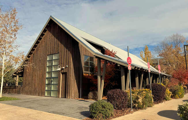 A wooden building with a green roof and a red and white sign in front.