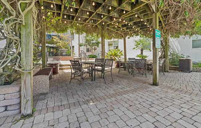 A patio with a pergola and chairs.