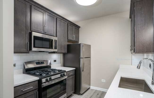 a kitchen with stainless steel appliances and dark wood cabinets