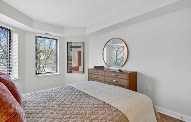 A bedroom with a large bed, a dresser, and a mirror.