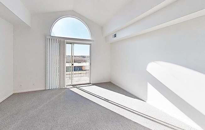 A living room with a cathedral ceiling, large window and a grey carpet at Brentwood Park Apartments in LaVista, NE
