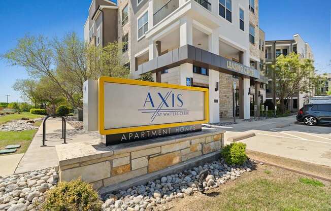 A sign for Axis Apartments in front of a building.