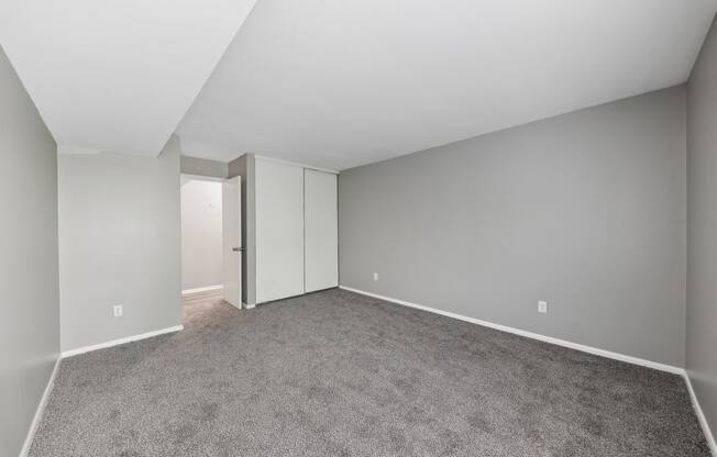 an empty living room with gray carpet and white walls