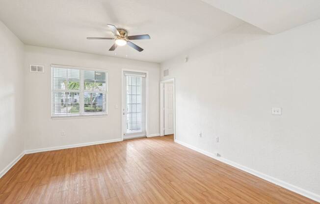 A room with a ceiling fan and wooden flooring.
