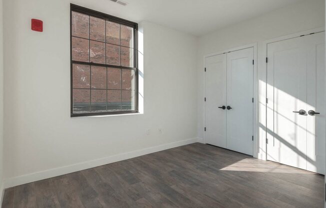 a bedroom with white walls and a window and a door
