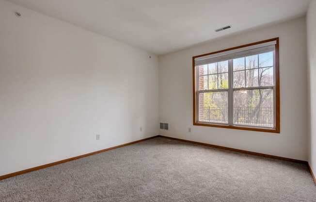 an empty living room with a large window and carpet