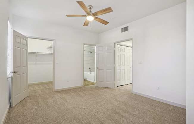 the living room of an empty apartment with white walls and a ceiling fan