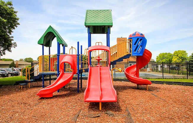 a playground with a red slide and a yellow and blue slide