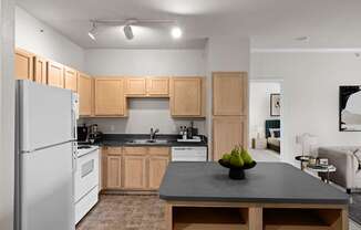 A kitchen with oak cabinets, white appliances, track lighting and a kitchen island with storage.