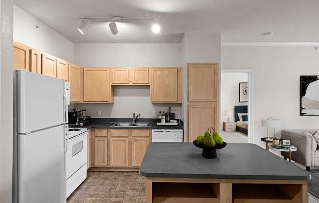 A kitchen with oak cabinets, white appliances, track lighting and a kitchen island with storage.