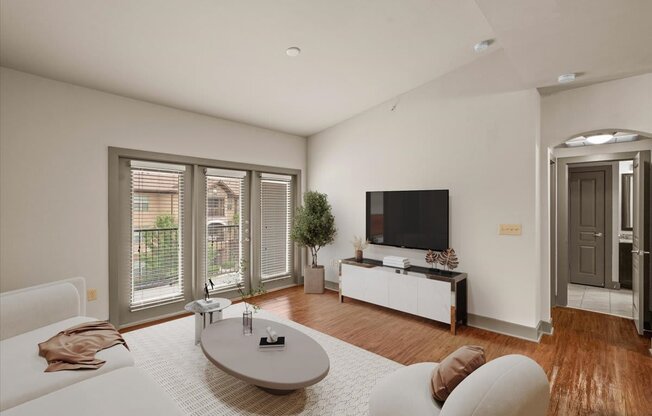 a living room with a white couch and a tv on the wall