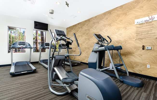 a gym with cardio equipment and weights on a wall