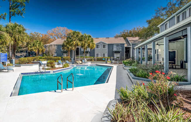 A swimming pool surrounded by a concrete floor and a building with a glass door.