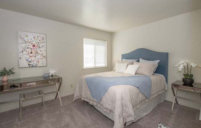 A bedroom with a bed, nightstand, and a painting on the wall at Zinfandel Village Apartments, California, 95670