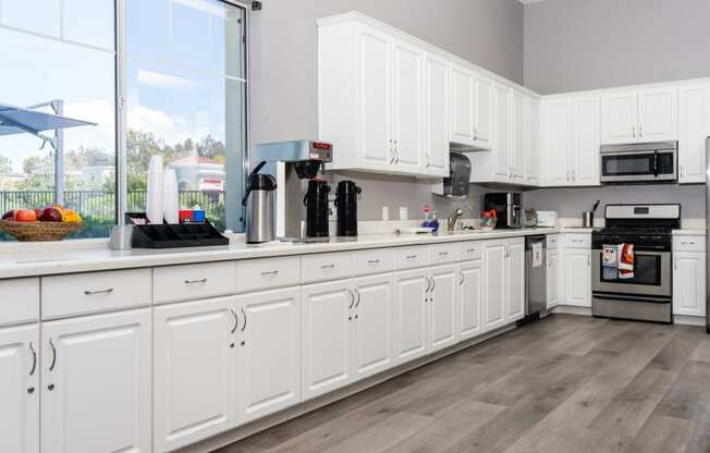 a large kitchen with white cabinets and a large window