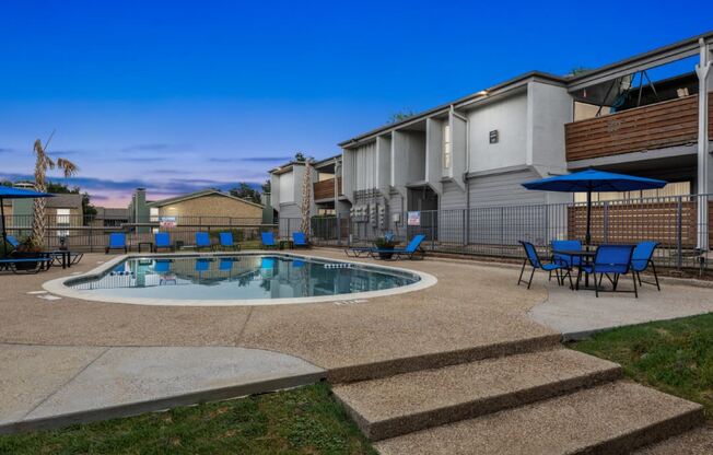 a resort style pool with chairs and umbrellas in front of a building