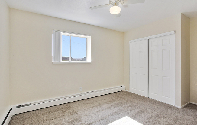 Bright and cozy bedroom featuring plush carpeting, elegant white trim, and a large window for ample natural light.