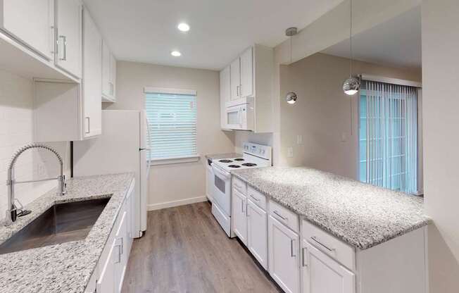 A kitchen with white cabinets and a granite countertop.