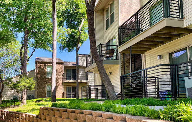 A tree in front of a building with a balcony.
