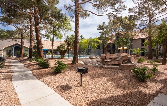 a backyard with a pool and trees and a sidewalk